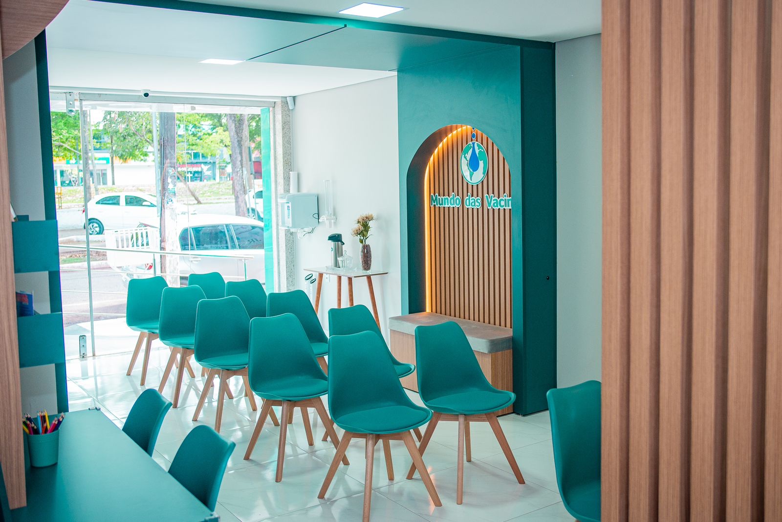 Sala de espera da Mundo das Vacinas, com cadeiras em tom de água e a arcada de madeira com o logo ao fundo