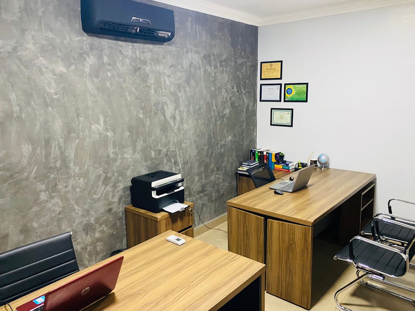 Sala de atendimento com mesa de madeira, notebook e cadeiras