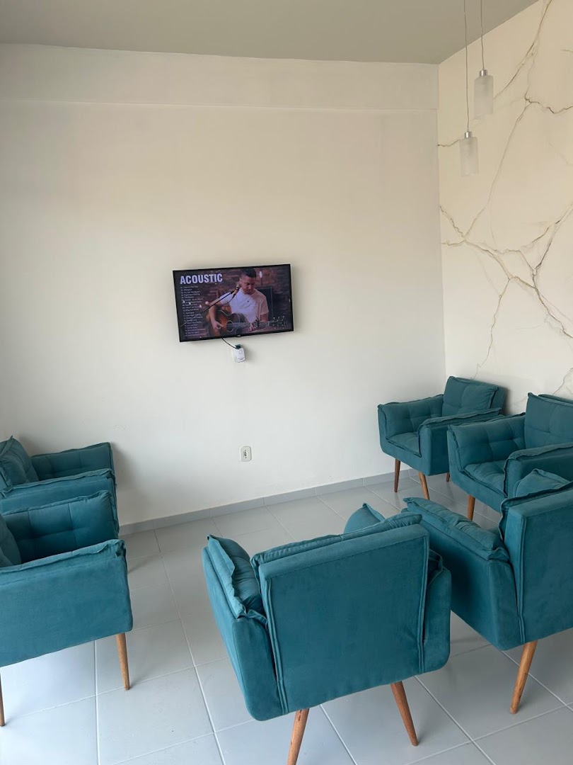Sala de espera com poltronas azul-petróleo e TV na parede