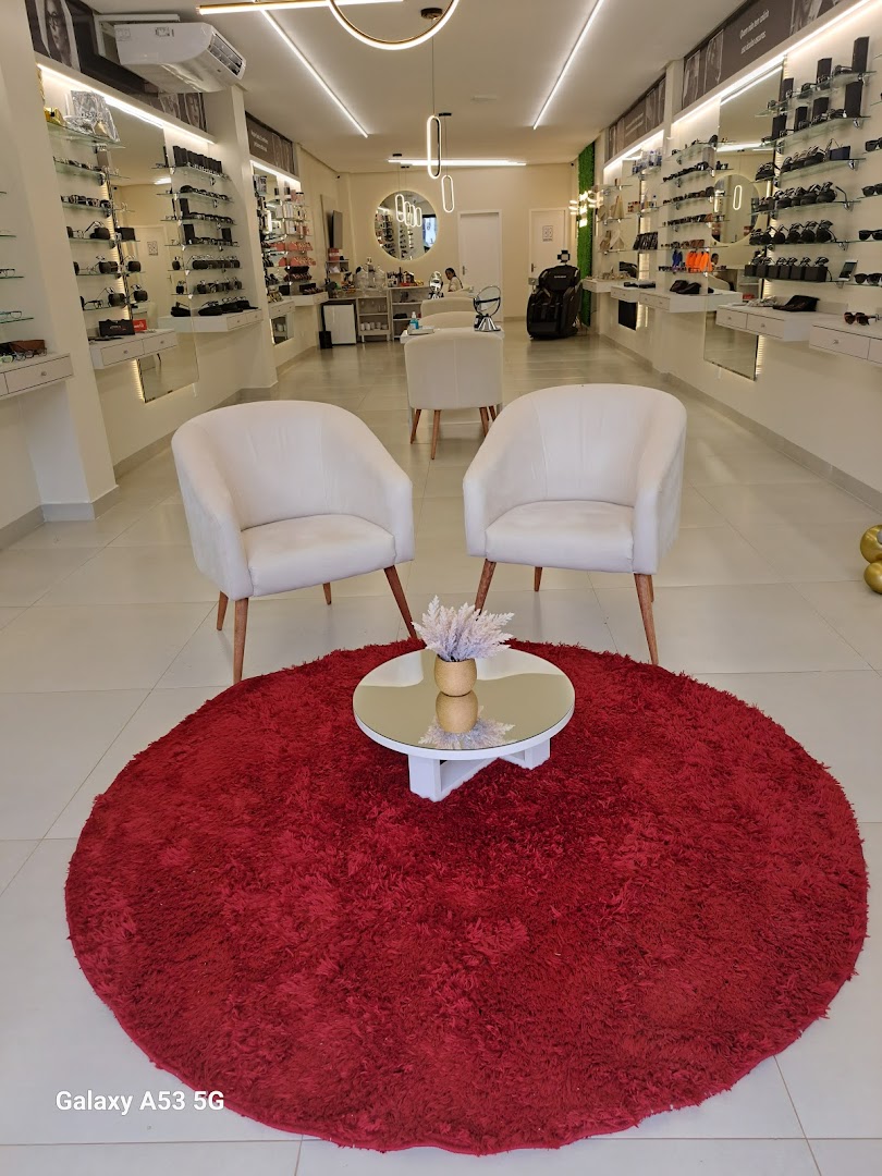 Espera da loja com poltronas claras sobre tapete vermelho redondo