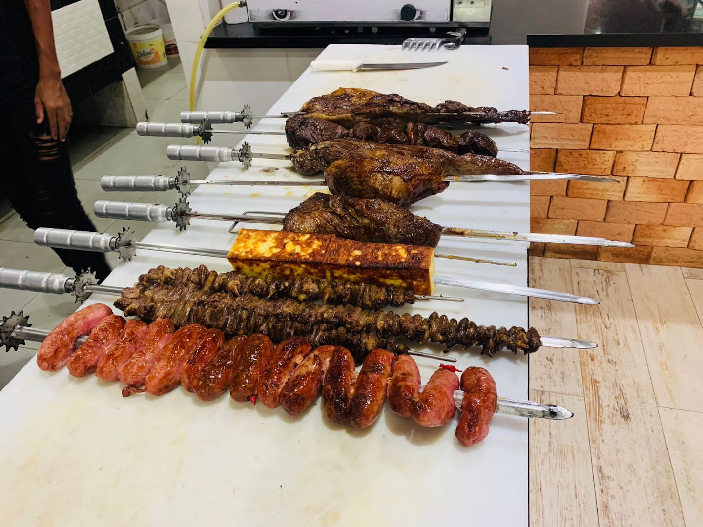 Espetos de churrasco variados assando na grelha: picanha, linguiça e queijo coalho
