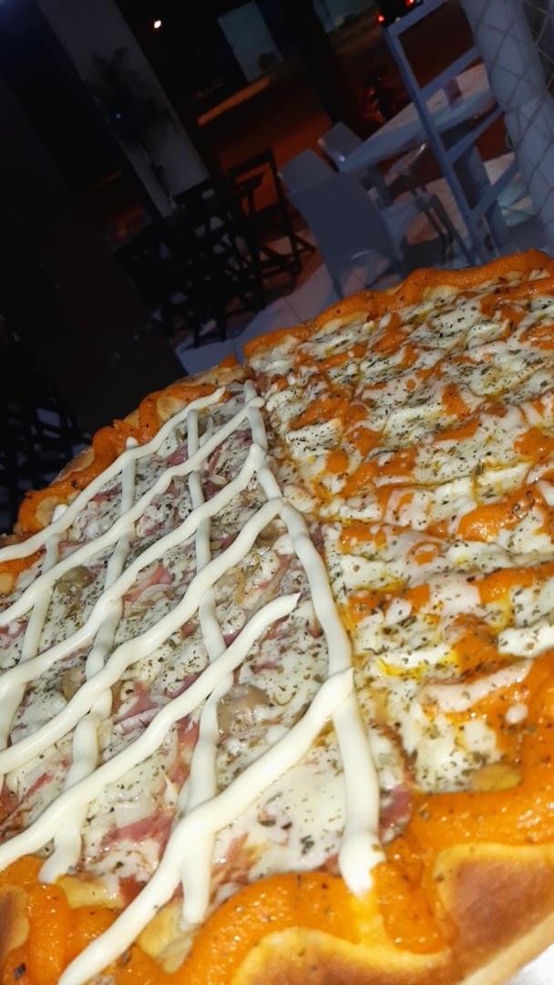 Pizza artesanal com fio de molho branco e coberturas variadas, vista de perto