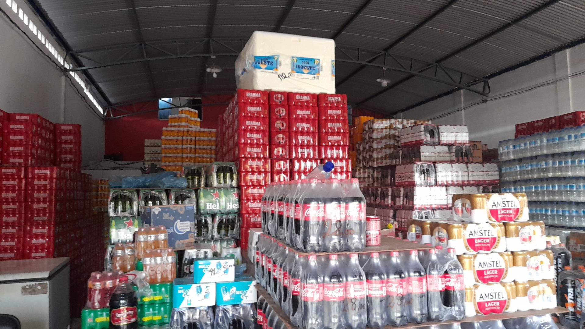 Pilhas de fardos e engradados de bebida dentro do depósito