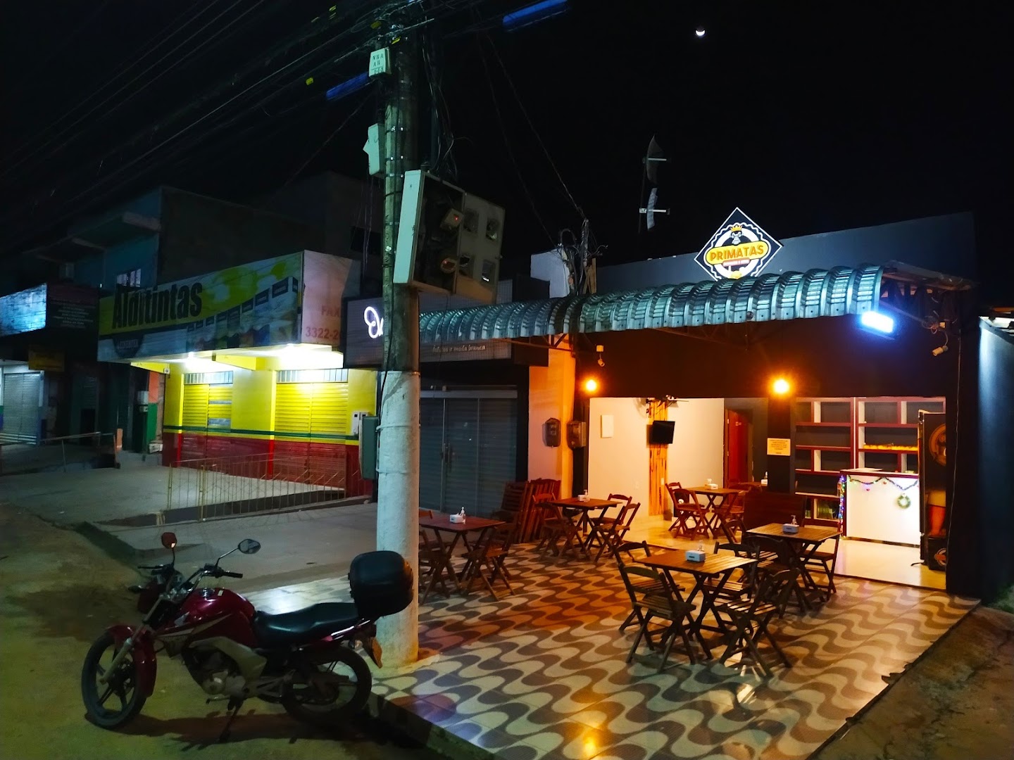Fachada da Primatas à noite, com mesas na calçada