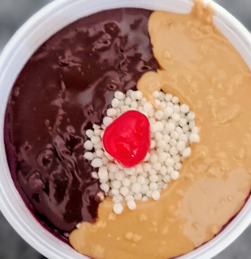 Açaí com pasta de amendoim, calda e uma cereja no centro