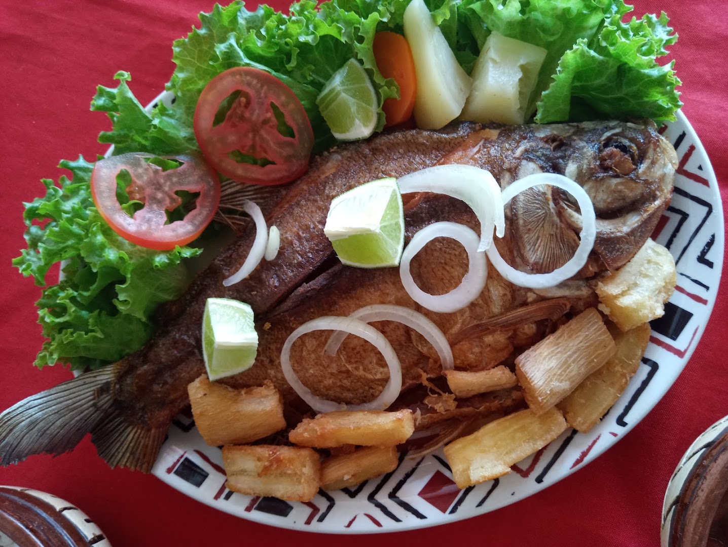 Peixe frito dourado com mandioca, salada e cebola