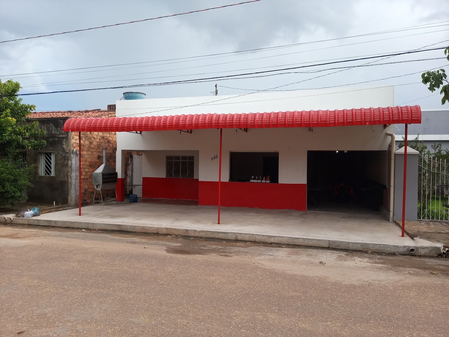 Fachada vermelha e branca do restaurante com toldo de telha vermelha