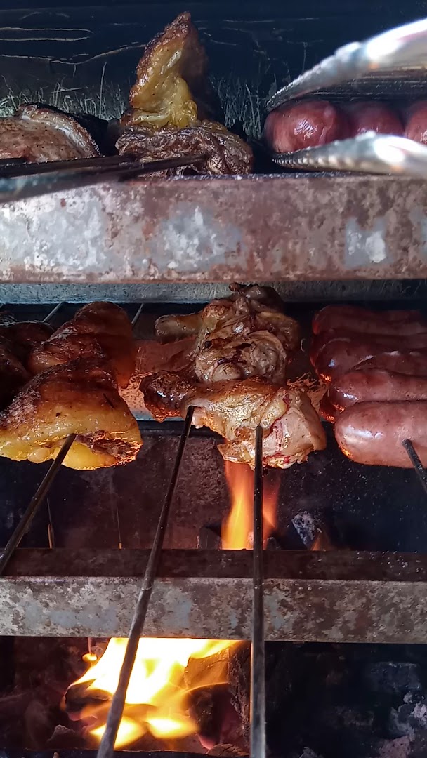 Carnes variadas assando na brasa, com linguiça e pernil dourando