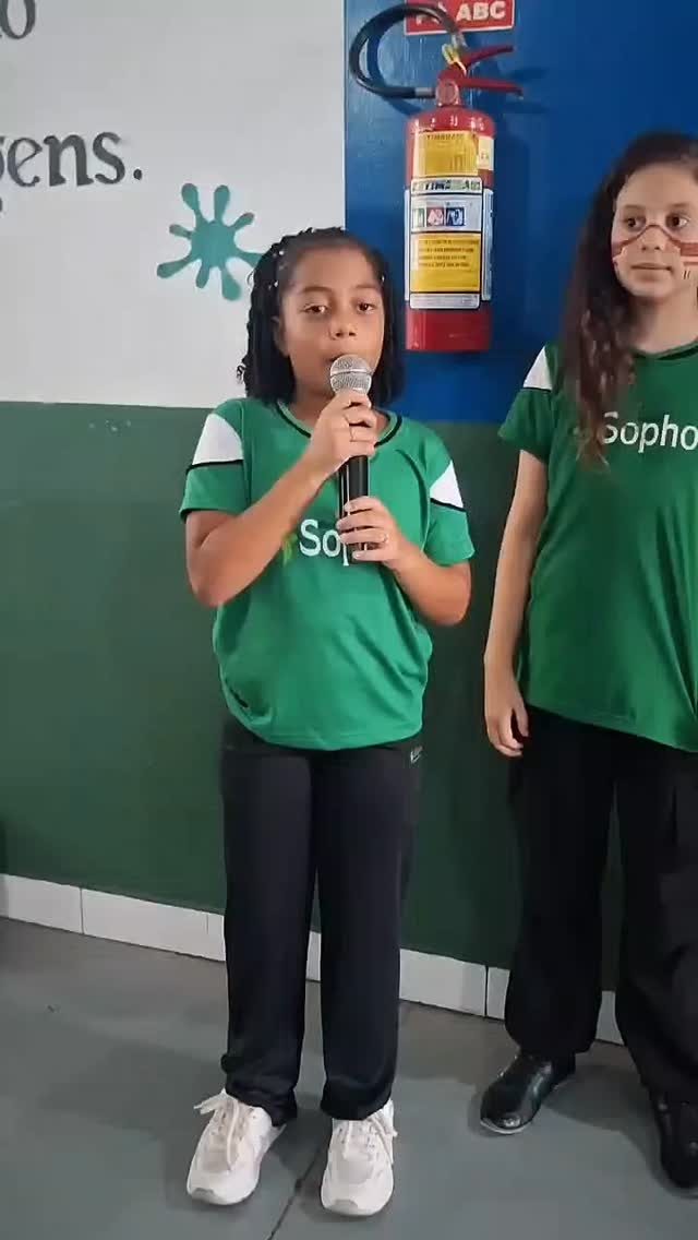 Alunas apresentando com microfone em sala