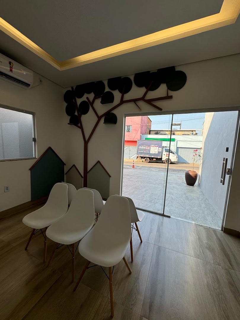 Sala de espera com poltronas e um mural de árvore na parede