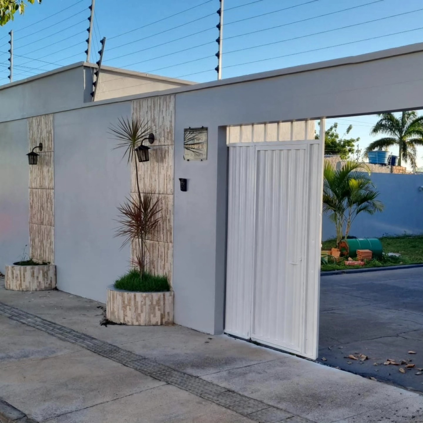Entrada de casa com portão branco e jardim