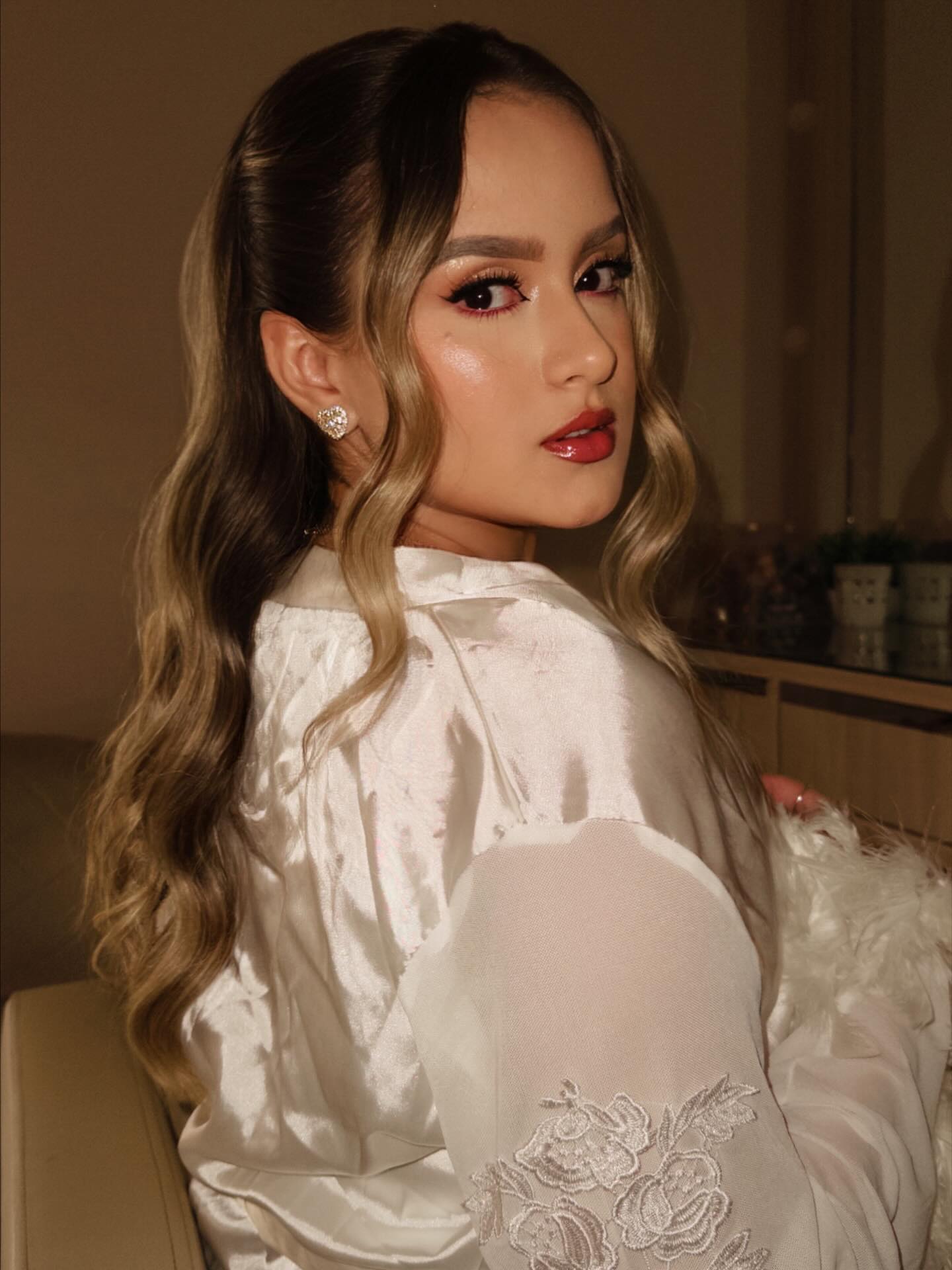 Cliente de perfil com make de festa e batom vermelho