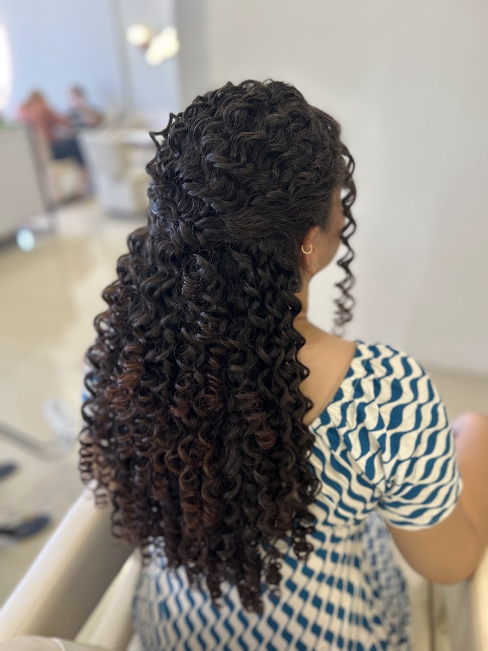 Cliente do Studio C com cabelos cacheados finalizados, resultado de um trabalho de cachos no salão.