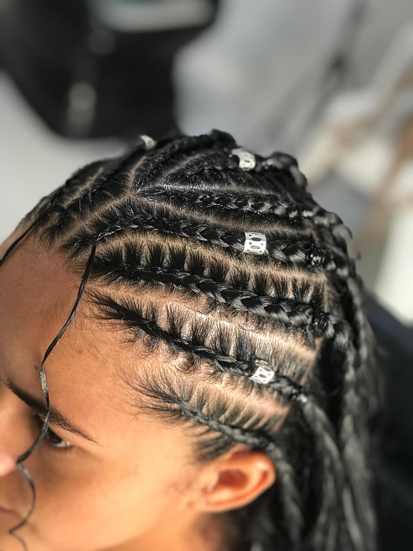Detalhe de tranças cornrows bem alinhadas com miçangas