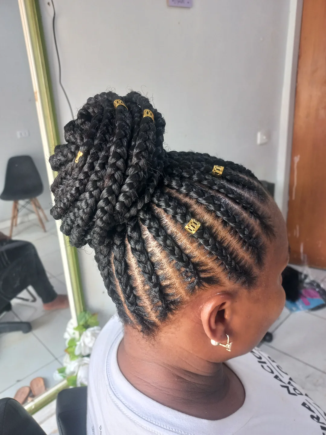 Coque alto feito de tranças box braids com miçangas douradas