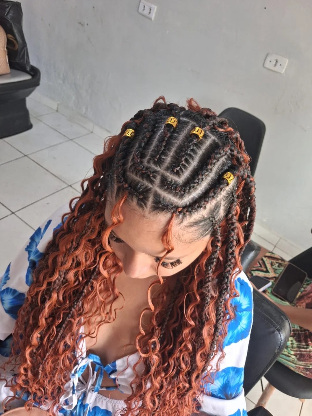 Box braids com pontas cacheadas em tom cobre e miçangas douradas, vista de cima