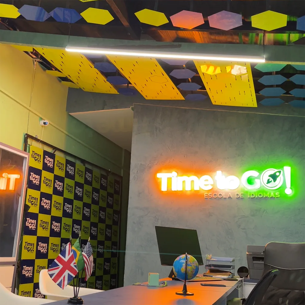 Interior da Time to Go com letreiro neon, globo terrestre e bandeiras na recepcao