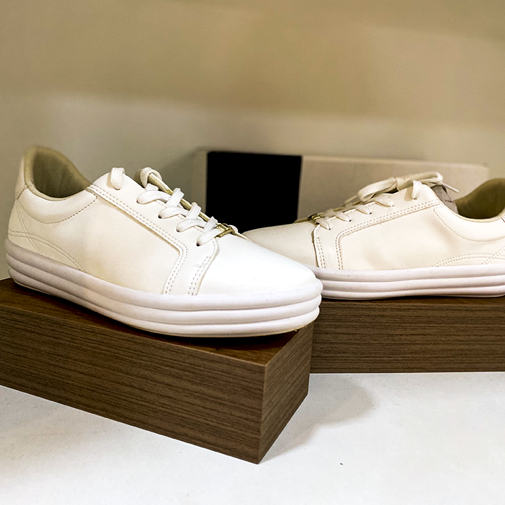 Tênis branco casual num pedestal de madeira