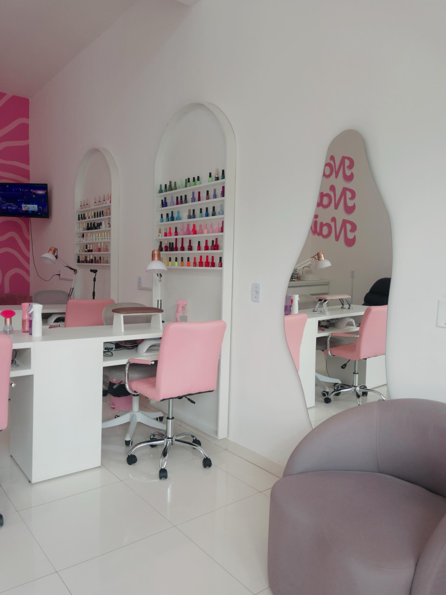 Interior do estúdio com neon LOVE, arcos e prateleiras de esmalte